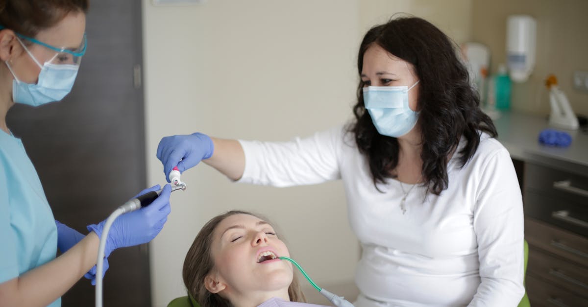 middle aged female lying in dental chair with tube suction in mouth while getting professional treat